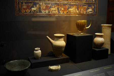 Jars made of limestone and ceramic, and a gold drinking cup with built-in straw displayed in The Wonders of Ancient Mesopotamia