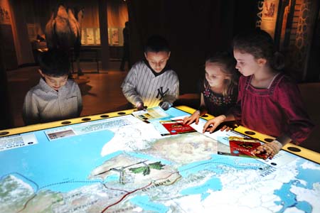 Children (holding their exhibition ‘passports’) with an interactive map of the Silk Road