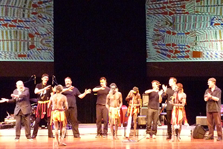 Benjamin Wilfred leads members of the Young Wägilak Group and the Australian Art Orchestra as they sing the painting by his grandfather, Sambo Barabara, The Dead Ones, projected on screen