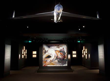 Long view of the gallery with the Captain S painting in the centre and a plane hanging from the ceiling