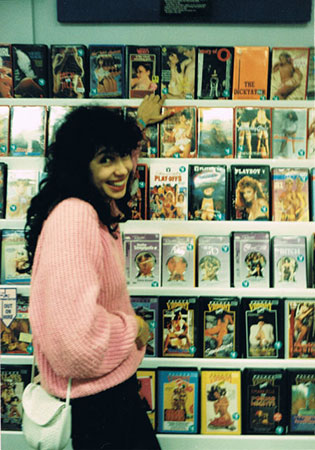 Nikki Stern at the local video shop, pointing to the Let’s Make Love video,