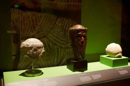 Showcase featuring (left) a stone wig dating from about 2500 BC, and (centre) a replica of the head of King Naram-Sin (about 2254–2218 BC)